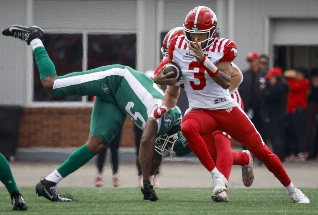 Saskatchewan Roughriders' Justin Weaver, left, dives for Calgary Stampeders quarterback Vernon Adams Jr. during first half pre-season CFL football action in Calgary, Monday, May 18, 2026. THE CANADIAN PRESS/Jeff McIntosh.