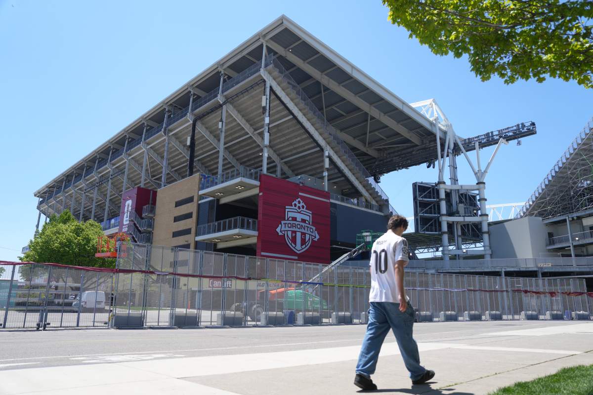 A soccer fan walks past BMO Field, Toronto's FIFA World Cup venue, while construction continues as the countdown to the opening game hits two weeks, in Toronto, Friday, May 29, 2026.