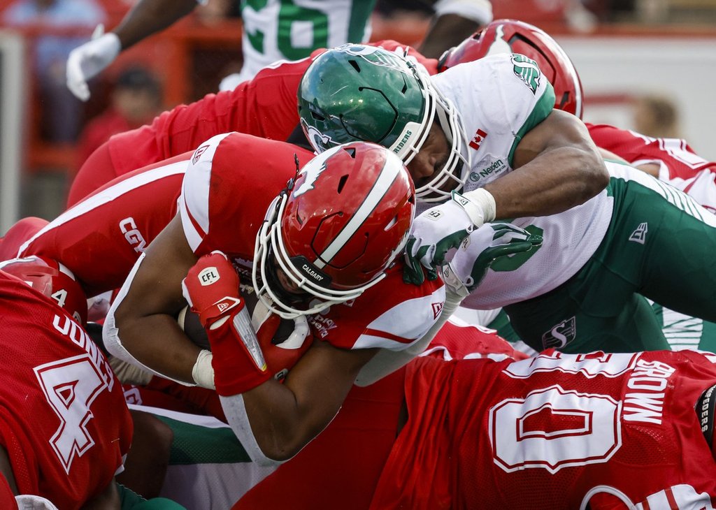 Saskatchewan Roughriders' Jameer Thurman tries to stop Calgary Stampeders quarterback Quincy Vaughn from scoring a touchdown during second half CFL action in Calgary, Saturday, June 20, 2026. THE CANADIAN PRESS/Jeff McIntosh.