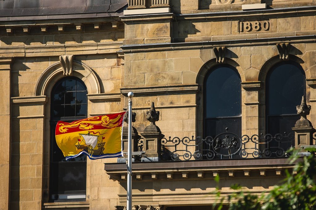 The New Brunswick flag flies in front of the Legislative Assembly Building, home of the provincial parliament, in Fredericton, Saturday, July 26, 2025. THE CANADIAN PRESS/Giordano Ciampini.
