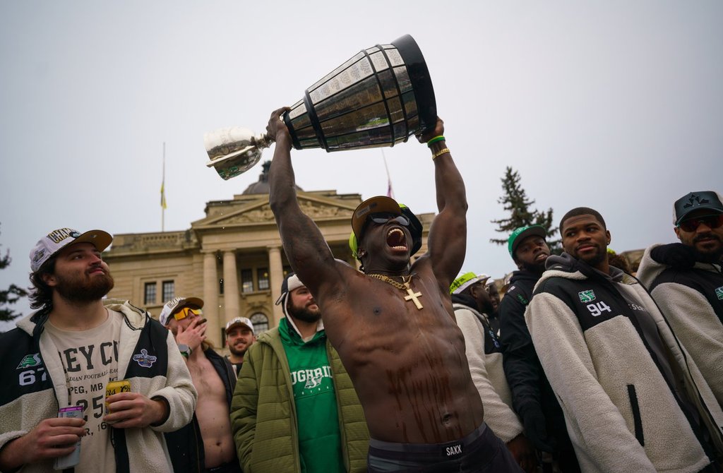 Saskatchewan Roughriders receiver Ajou Ajou lifts the Grey Cup during a Grey Cup championship parade in Regina, Tuesday, Nov. 18, 2025. The Saskatchewan Roughriders defeated the Montreal Alouettes on Sunday to become Grey Cup champion for the fifth time in team’s history. THE CANADIAN PRESS/Heywood Yu.