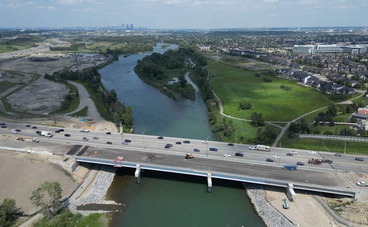 Paving crews are putting the final touches on the new Ivor Strong Bridge (bottom), over the Bow River, before its scheduled opening on July 27, 2026.