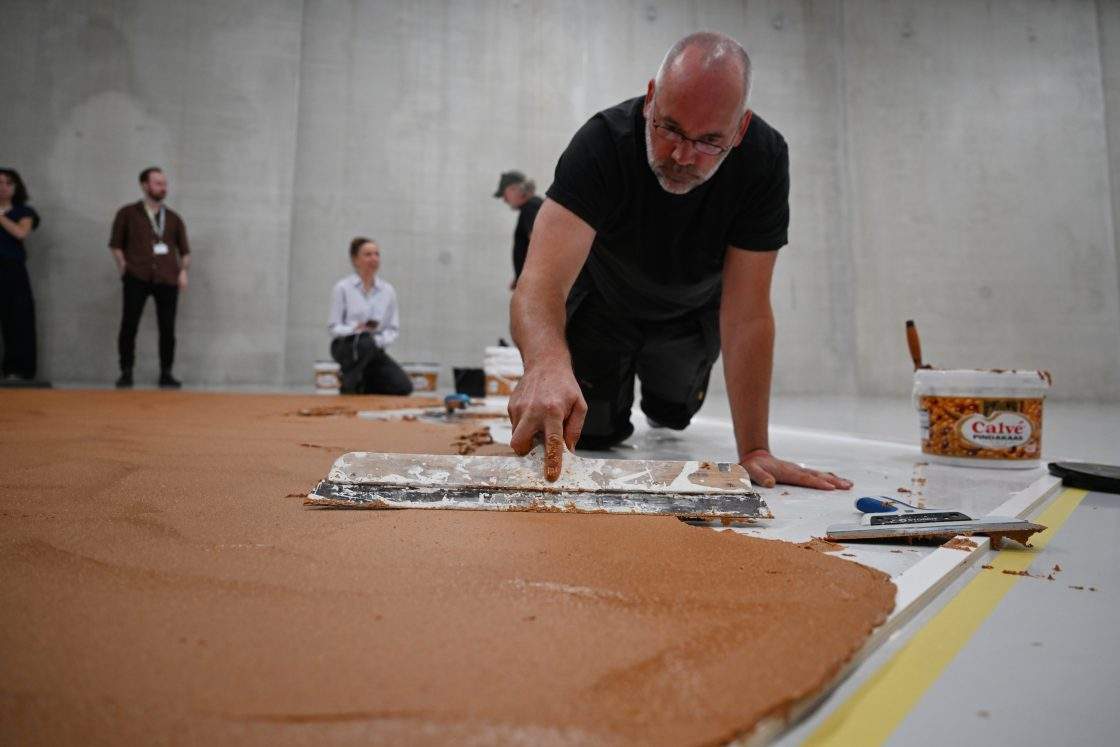 Workers spread peanut butter on a floor to recreate the "Peanut Butter Floor" artwork in tribute to Dutch artist Wim T. Schippers at the Museum Boijmans Van Beuningen in Rotterdam, Netherlands, Friday, July 3, 2026.